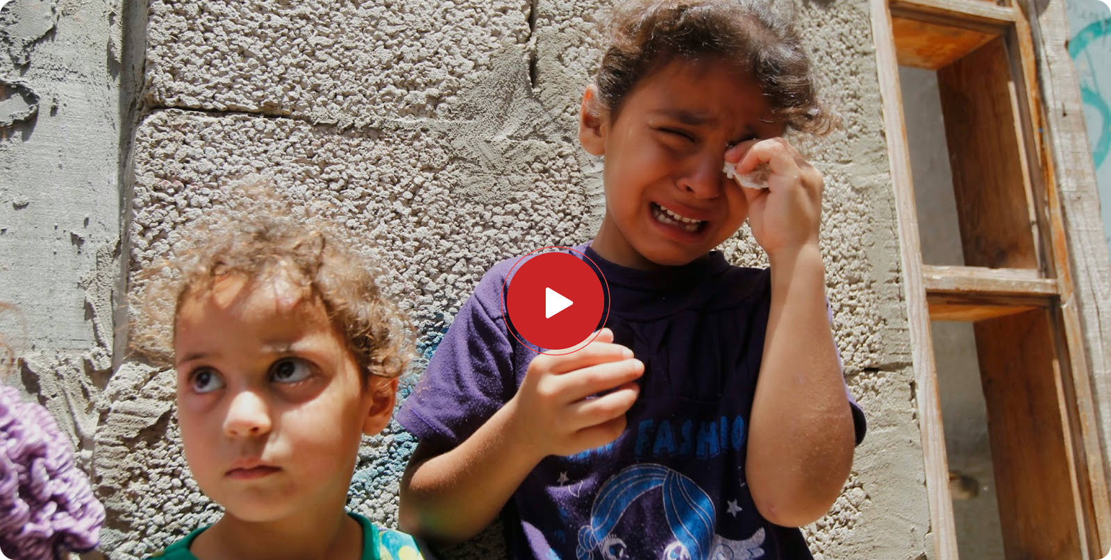 A girl next to her sister, crying, from Gaza